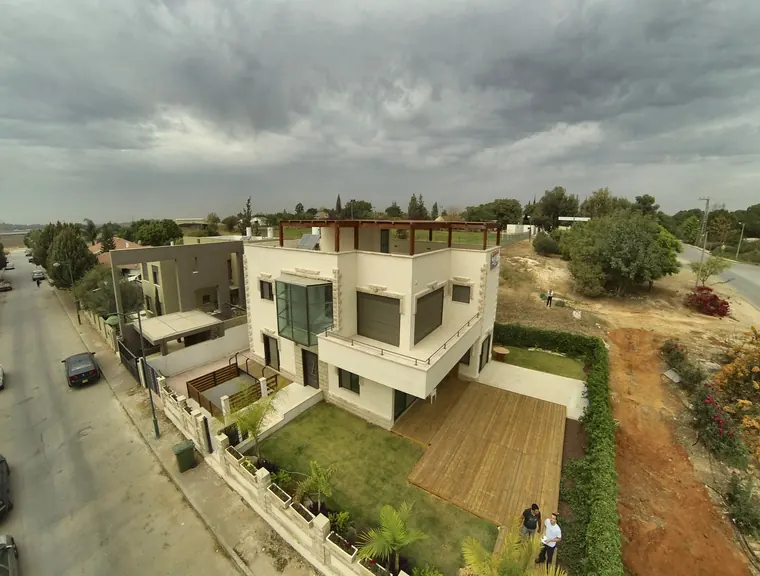 מבט על הדק והגינה לצד הבית, עם שני אנשים בגינה לקנה מידה